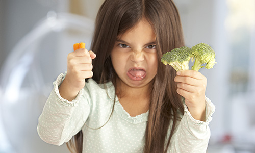 Fussy eating - girl turning her nose up at vegetables