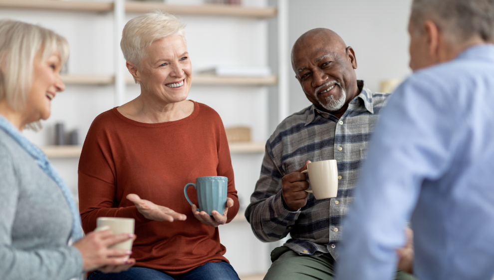 Group of people sat in a circle talking with cups of tea