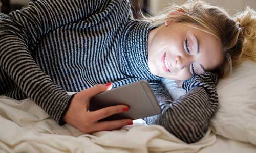 Young girl on her phone in bed