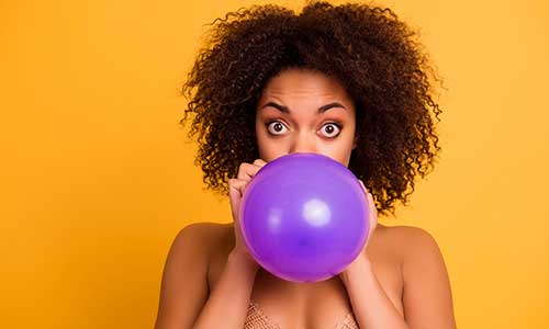 Ovarian cancer, bloating - woman blowing up balloon