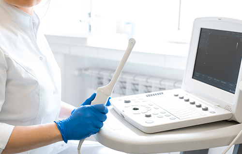 A gynecologist sets up an ultrasound machine. A transvaginal ultrasound scanner of the internal organs of the pelvis. Female health concept.