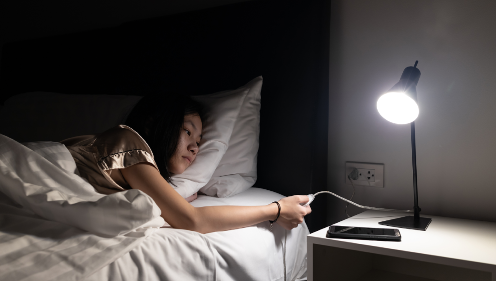 A teenage girl turning off her lamp before going to sleep