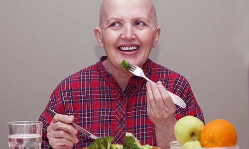 Cancer nutrition - woman with cancer eating healthy vegetables