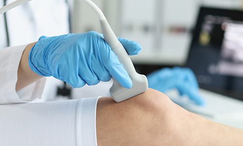 Orthopedic doctor makes ultrasound examination of a patients knee in clinic