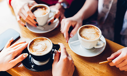 Women catching up over coffee - only the coffee cups in focus