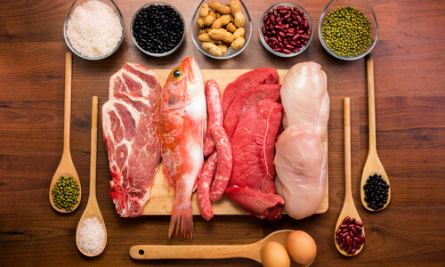 Selection of fish, meat, eggs and grains on a wooden board