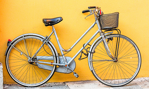 Bike with basket leaning on yellow wall