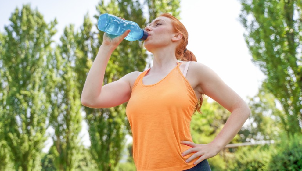 A woman rehydrates on some water during her summer run