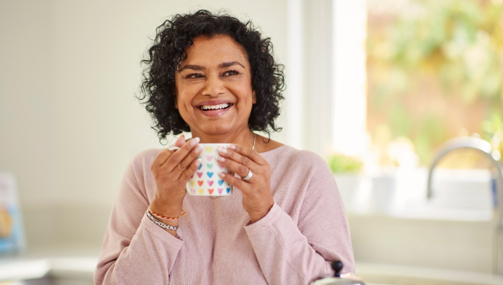 A woman enjoys a hot drink in her kitchen