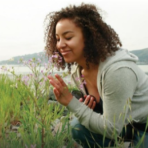 A woman practices mindfulness by admiring the flowers
