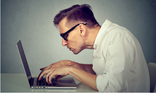 Man leaning uncomfortably over his computer at a desk